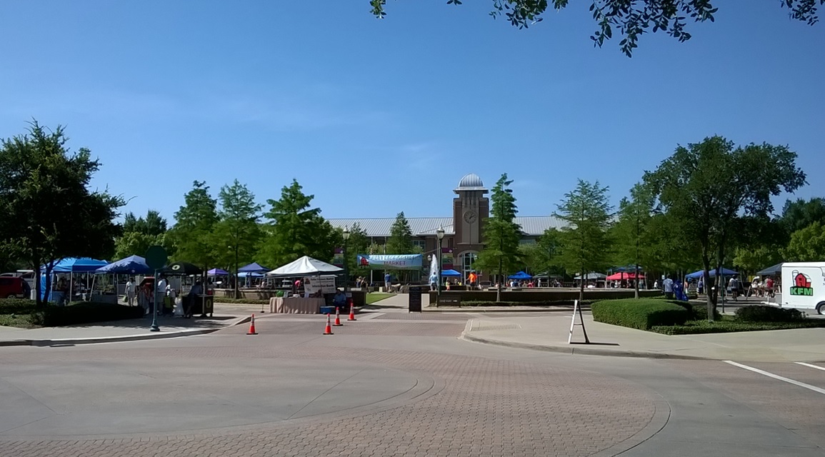 People meeting and browsing the Keller farmers market outside Town Hall in July 2015